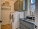 Well-lit laundry room featuring a modern washer and dryer, green cabinets and floating shelves at 270 Alcovy Reserve Way, Covington, GA 30014