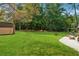 Well-maintained backyard with lush green lawn, mature trees, and patio area at 461 Village Green Sw Ct, Lilburn, GA 30047