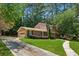 View of the garage and front entrance of a brick home with landscaped lawn and mature trees at 461 Village Green Sw Ct, Lilburn, GA 30047