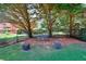 Landscaped backyard with a metal bench and flower pots, nestled under mature trees, perfect for relaxation at 781 Templeton Dr, Loganville, GA 30052