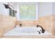 Soaking tub featuring beige tile surround and a window for natural light at 781 Templeton Dr, Loganville, GA 30052