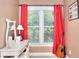 Corner of a bedroom featuring a white desk, mirror, and a guitar, illuminated by natural light through red curtains at 781 Templeton Dr, Loganville, GA 30052
