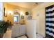 Cozy bathroom featuring a vanity, decorative mirror, hanging plants, and a blue and white striped shower curtain at 3099 Farmington Se Dr, Atlanta, GA 30339