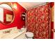 Well-maintained bathroom with single vanity, round mirror, patterned shower curtain and red walls at 3099 Farmington Se Dr, Atlanta, GA 30339