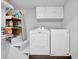 Compact laundry area with white washer and dryer, cabinet and shelving, maximizing storage space at 4066 Covered Bridge Sw Rd, Smyrna, GA 30082