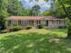 Charming one-story brick home featuring a well-maintained lawn and mature trees at 2000 Stone Mountain Lithonia Rd, Lithonia, GA 30058