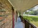 A cozy, covered side porch with brick wall and wood railing at 2000 Stone Mountain Lithonia Rd, Lithonia, GA 30058