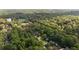 An aerial view shows a beautiful neighborhood nestled in a lush green forest with a pond and mature trees at 3390 River Ferry Dr, Alpharetta, GA 30022