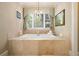 Elegant bathroom features a soaking tub with stone surround and decorative chandelier at 3390 River Ferry Dr, Alpharetta, GA 30022