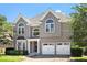 Charming two-story home with a two-car garage, arched windows, and neatly manicured landscaping at 4527 Village Springs Run, Dunwoody, GA 30338