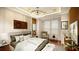Bright main bedroom with large windows, accent walls, a king bed, a sitting area, and a modern light fixture at 110 Serenity Pl, Fayetteville, GA 30214