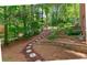 Landscaped backyard with a winding stone path and tiered retaining walls at 140 Longwater Cv, Roswell, GA 30075