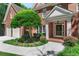 Close-up of beautiful brick home with two-car garage, manicured lawn and mature trees at 140 Longwater Cv, Roswell, GA 30075