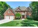 Beautiful brick home with a well-manicured lawn, a two car garage, and mature trees at 140 Longwater Cv, Roswell, GA 30075