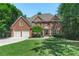 Beautiful brick home with a well-manicured lawn, a two car garage, and mature trees at 140 Longwater Cv, Roswell, GA 30075