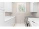 Functional laundry room featuring white cabinets and modern washer/dryer units at 140 Longwater Cv, Roswell, GA 30075