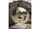 A custom stone archway offers a framed view of the backyard fire pit, lawn, and surrounding trees at 245 Roycroft Ln, Fayetteville, GA 30214