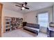 Bedroom featuring ceiling fan, a gray sofa, and three bookshelves containing books at 4191 Secret Shoals Way, Buford, GA 30518