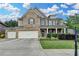 Charming brick two-story home with a manicured front lawn, three car garage, and covered front porch at 4191 Secret Shoals Way, Buford, GA 30518