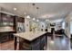Open kitchen features an island with seating, granite counters, dark cabinets, and stainless steel appliances at 4191 Secret Shoals Way, Buford, GA 30518