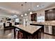 Open kitchen features an island with seating, granite counters, dark cabinets, and stainless steel appliances at 4191 Secret Shoals Way, Buford, GA 30518
