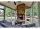 Inviting sunroom featuring a brick fireplace, ceiling fan and comfortable striped furniture at 4191 Secret Shoals Way, Buford, GA 30518
