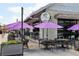 Charming patio with elegant outdoor furniture, string lights and purple umbrellas at Cattle Shed wine & steak bar at 6815 Halcyon Way, Alpharetta, GA 30005