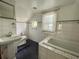 The bathroom has white tiled walls, black and white tile floor, tub and pedestal sink at 1238 Trenton St, Atlanta, GA 30316