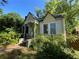 Cute bungalow-style home with yellow siding, shuttered windows, and overgrown greenery at 1238 Trenton St, Atlanta, GA 30316
