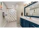 Bright bathroom featuring a modern vanity with blue cabinetry, white countertop, and a shower with a pineapple-themed curtain at 2356 Defoors Ferry Nw Rd, Atlanta, GA 30318
