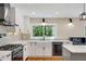 Updated kitchen with white cabinetry, modern appliances, marble countertops, and stylish backsplash at 2356 Defoors Ferry Nw Rd, Atlanta, GA 30318