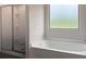 Bathroom features a walk-in shower, soaking tub, and frosted glass window at 3062 Hawthorn Farm Blvd, Loganville, GA 30052