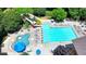 Aerial view of a community swimming pool with a slide and splash pad, surrounded by lounge chairs and lush landscaping at 3715 Horizon Ct, Cumming, GA 30041