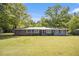 Charming single-story home with a metal roof, brick accents, manicured landscaping, and a large front yard at 4715 Howard Dr, Powder Springs, GA 30127