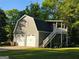 Two-story garage with white garage doors, exterior stairs, and a charming upper level at 4715 Howard Dr, Powder Springs, GA 30127