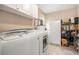 Bright laundry room featuring a washing machine, dryer, and storage shelves for household supplies at 4715 Howard Dr, Powder Springs, GA 30127