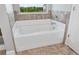 Bright bathroom featuring white soaking tub framed by decorative tile at 4171 Towncastle Ln, Buford, GA 30518