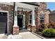 Inviting front porch with brick columns, a stylish door, and manicured landscaping at 4171 Towncastle Ln, Buford, GA 30518