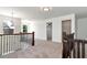 An open loft area with neutral carpeting, wooden railings, and natural light from nearby windows at 4171 Towncastle Ln, Buford, GA 30518