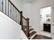 Wooden staircase with dark iron railing leading to the next floor and a view of the bathroom at 4171 Towncastle Ln, Buford, GA 30518