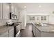 Open kitchen features granite countertops, stainless steel appliances, and dark hardwood floors at 1626 Palladian Way, Lithonia, GA 30058