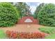 Community entrance featuring a brick sign surrounded by lush greenery and colorful flowers, displaying neighborhood name and patriotic flag at 4975 Duncans Lake Dr, Buford, GA 30519