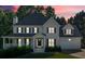 Two-story home at dusk featuring a covered front porch, attached garage, well-manicured lawn and shade trees at 185 Waverly Walk, Douglasville, GA 30134