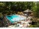 Community pool surrounded by trees, lounge chairs and umbrellas, perfect for summer relaxation and recreation at 6596 Wright Ne Rd, Atlanta, GA 30328