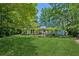View of a well-maintained backyard with lush green grass, mature trees, and a quaint pergola-covered patio at 3299 Pete Shaw Rd, Marietta, GA 30066
