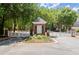 Charming community entrance gate with brick pillars, white fencing, and beautiful landscaping at 4905 Village Green Dr, Roswell, GA 30075