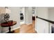 Upstairs hallway featuring hardwood floors, staircase with white spindles, laundry room, and decorative table at 4905 Village Green Dr, Roswell, GA 30075