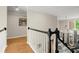 Bright hallway featuring hardwood floors, staircase with white spindles, and an elegant chandelier in the background at 4905 Village Green Dr, Roswell, GA 30075