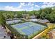 Aerial view showcases tennis courts and a refreshing pool, all nestled within a lush, tree-filled landscape at 4905 Village Green Dr, Roswell, GA 30075