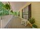 Inviting covered porch featuring a porch swing and rocking chair on a sunny day in a wooded setting at 4950 Creel Rd, Chattahoochee Hills, GA 30213
